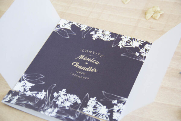 O convite para casamento simples "Compton" contém fundo de cor com apontamentos florais. Fecha com papel translúcido e com faixa impressa ou cordel.