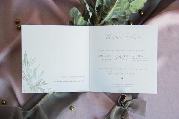 O convite de casamento floral com cor Algona é composto por papel texturado, design rico em floral e faixa em tecido rasgado verde tropa.