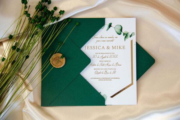 O convite casamento verde e dourado Bellevue contém envelope verde, lacre dourado e cartão branco com brilho dourado e ramos verdes de eucalipto