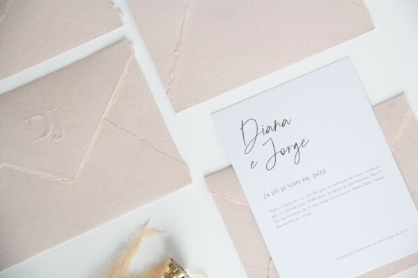 Convite de casamento simples e moderno, contém envelope em papel artesanal rosa, iniciais com relevo e cartão liso com design minimalista